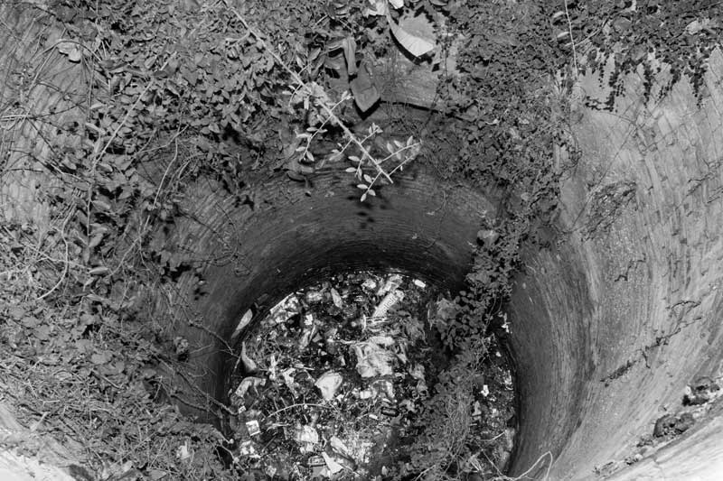 Household waste including remains from religious observances being dumped into a well once used as a drinking water source in Bhojpur district, Bihar